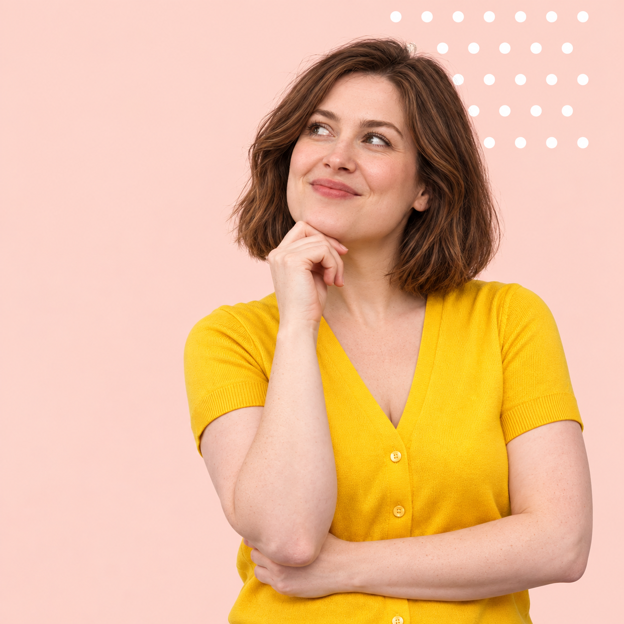 Woman in yellow smiling thoughtfully with her hand under her chin